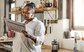 istock Smiling African American woman reading the newspaper in the morning 1179978472