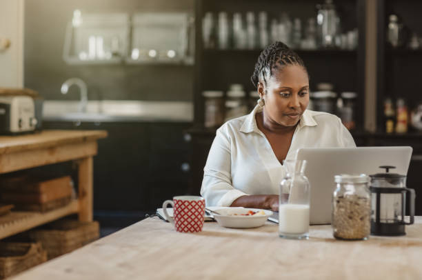 African American woman using a laptop over breakfast at home