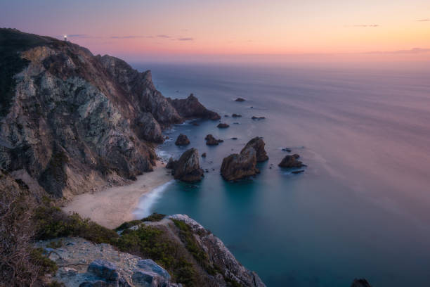 zachód słońca nad ukrytą surrealistyczną plażą praia da ursa. cabo da roca z latarnią w tle. wybrzeże atlantyku, portugalia, europa - cabo da roca zdjęcia i obrazy z banku zdjęć