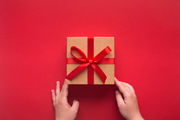 istock New year gift in woman hands on red background 1179979474