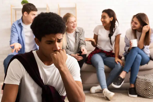 Discrimination concept. Upset guy feeling lonely, avoid talking to teens