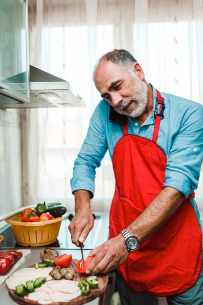 istock Mature man preparing food in the kitchen and using smart phone 1179980215