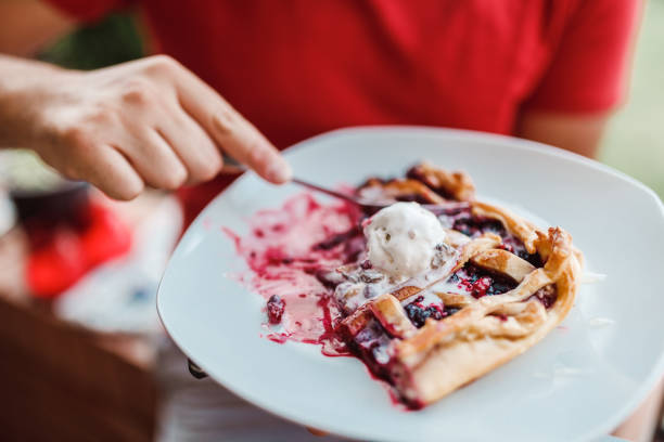 mann isst stück kirschtorte mit vanille-topping - pie dessert cherry pie baked stock-fotos und bilder
