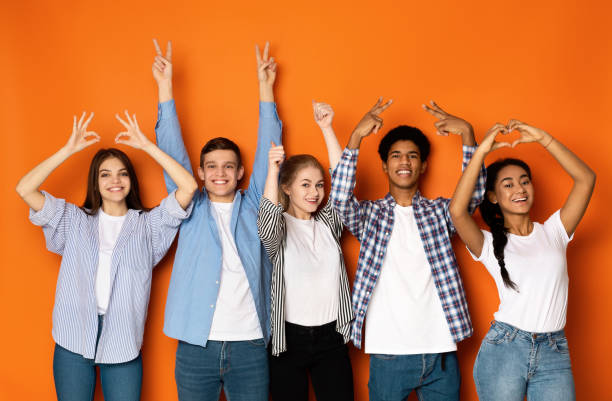 young friends gesturing with hands over orange background - dream time imagens e fotografias de stock