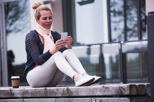istock Blondie female student holding mobile phone. 1179984542