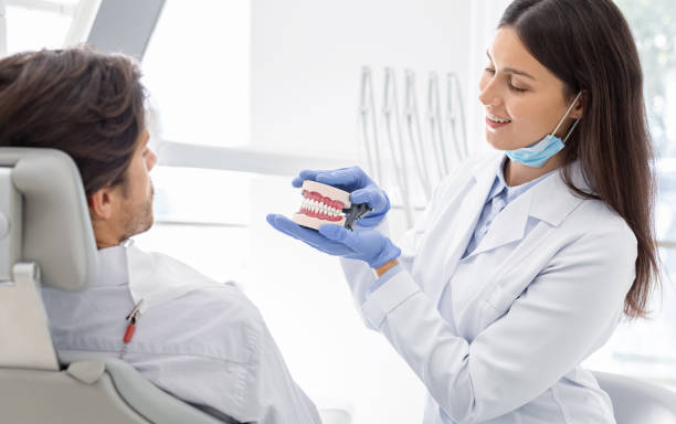 bonito dentista mostrando su modelo de mandíbula paciente - premolar fotografías e imágenes de stock