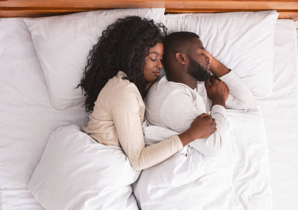 романтическая черная пара обнимается во время сна в постели - couple affectionate relaxation high angle view стоковые фото и изображения
