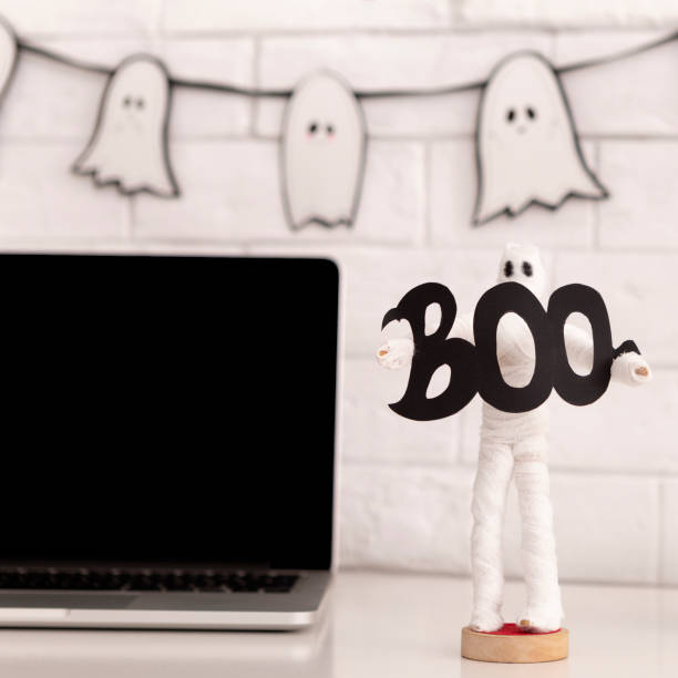 istock Laptop with blank screen and ghost holding boo text 1179986712