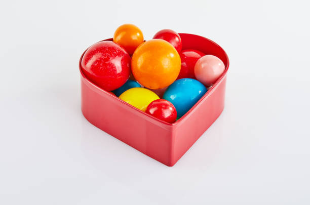 istock Multi colored balls of chewing gum on a white background in a red heart with reflection. 1179988826