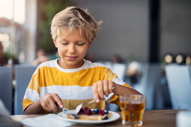 kleiner junge essen frühstück crepes mit früchten - eierkuchen speise stock-fotos und bilder