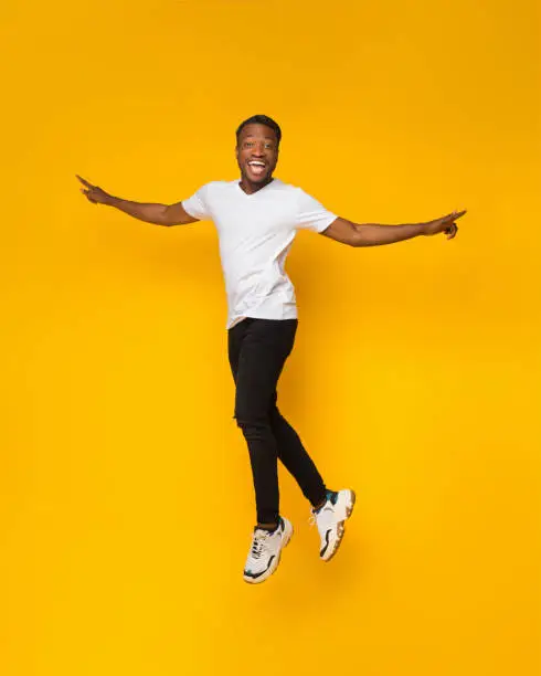 Photo of African American Guy Jumping Having Fun Over Yellow Background