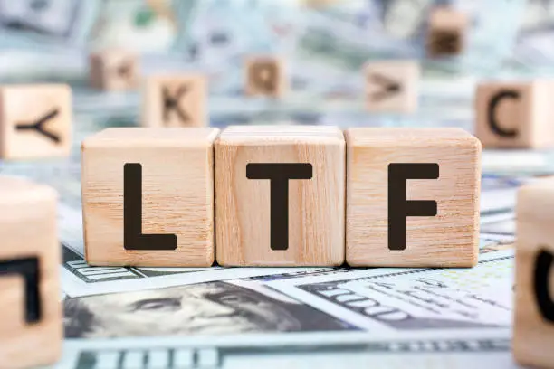 LTF - acronym from wooden blocks with letters, abbreviation LTF Long Term Equity Mutual Fund and RMF Retirement Mutual Fund concept, random letters around, money background