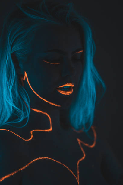 Close-up portrait in ultraviolet light. Face painted with glow