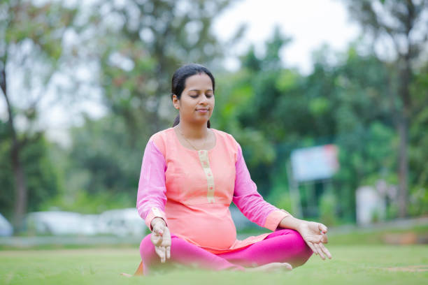 Pregnant woman's sitting in a position lotus stock photo Pregnant, Yoga, Women, Females south indian lady stock pictures, royalty-free photos & images