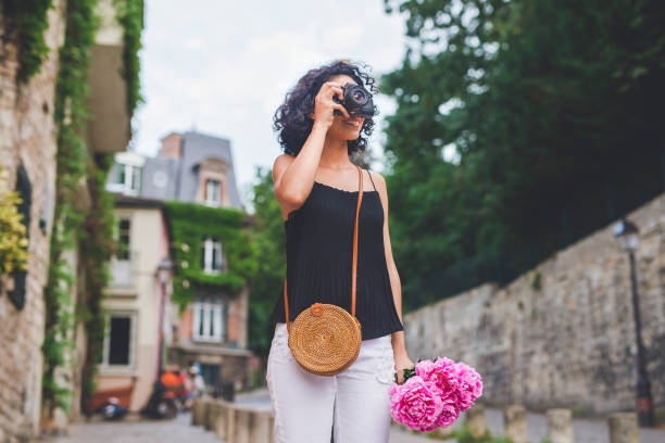 Shot of a young woman taking pictures with her camera while exploring a city