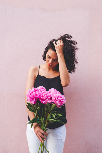 Shot of an attractive young woman posing with a bouquet against a pink background