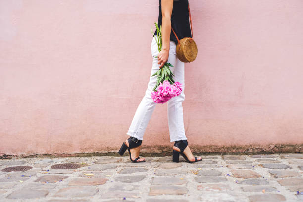 Cropped shot of an unrecognizable woman holding a bouquet while posing against a pink background