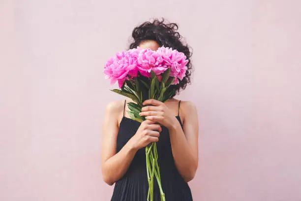 Cropped shot of a woman holding a bouquet of flowers in front of her face