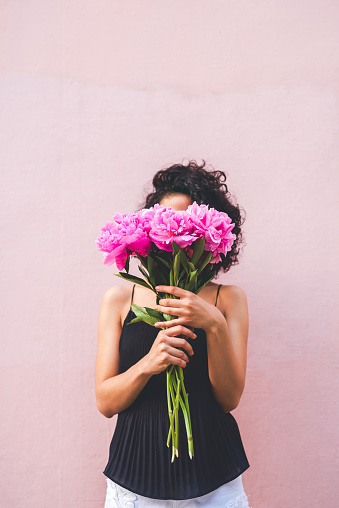 Cropped shot of a woman holding a bouquet of flowers in front of her face