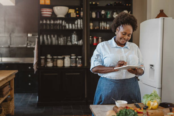 istock Smiling African American woman using a tablet while preparing dinner 1179997794