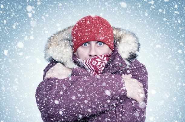 istock Frozen man in red winter clothes warms his hands, cold, snow, frost, blizzard 1179999499