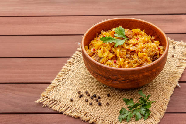 istock Stewed (braised) cabbage served on ethnic ceramic bowl. Traditional Polish Bigos with meat, aromatic pepper, fresh parsley 1179999552