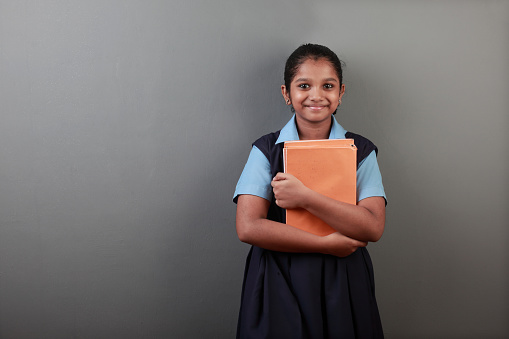 Portrait of young girl of Indian origin holding note books in her hands