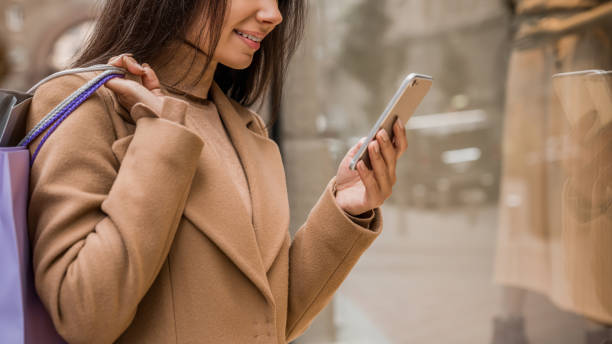 istock Cropped shot of attractive woman using smartphone while shopping 1180001088