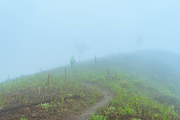 Backpacker Hiking On Mountain Peak Cliff after heavy rain with fog background
