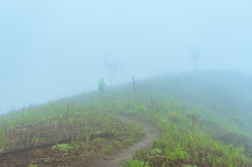 Backpacker Hiking On Mountain Peak Cliff after heavy rain with fog background