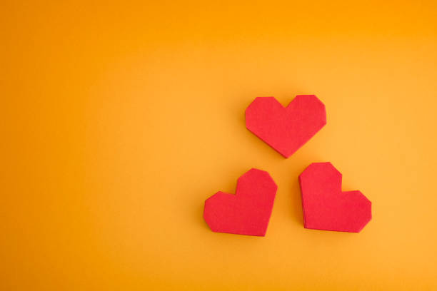 istock Three red origami hearts on a yellow background 1180009000