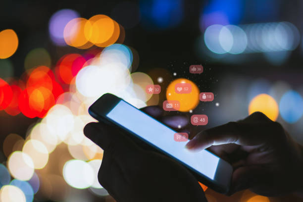 istock Soft focus man using his mobile phone or smartphone with  icons on night street bokeh background ,Businessman using ,Social, media, Marketing concept. 1180010680