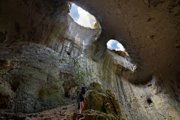 A young girl looks at the "Eyes of God" in "Prohodna" cave near Karlukovo village/ Bulgaria stock photo