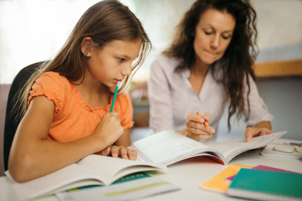 istock Girl doing homework with her mother at home 1180013031