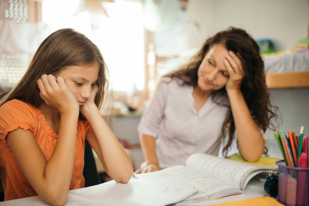 istock Girl doing homework with her mother at home 1180013108