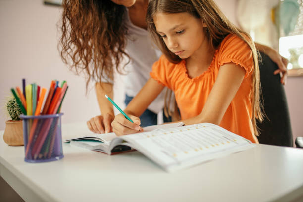 istock Girl doing homework with her mother at home 1180013183