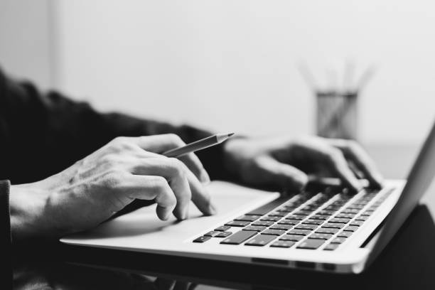 istock male student working on laptop computer with pencils. black and white 1180016575