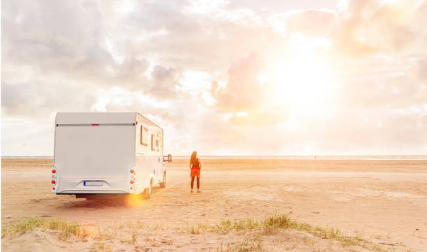 istock Woman at sunset  with mobile home on the beach 1180017832
