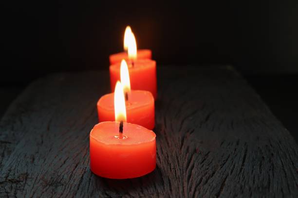 istock Burning red candles on black wooden background 1180017886