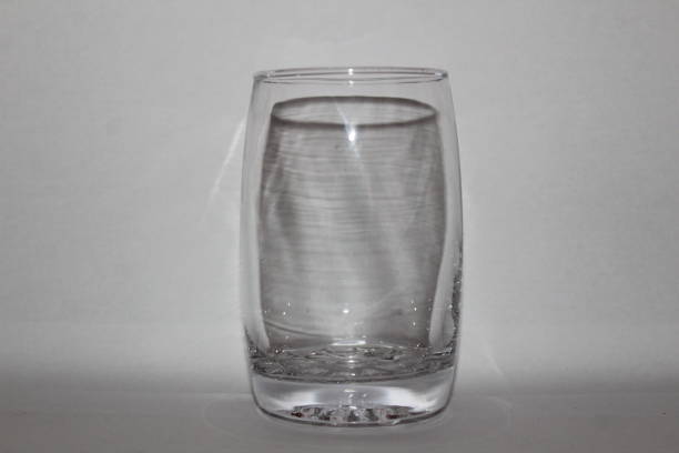 istock Single empty transparent / white glass with white background and shadow 1180018350