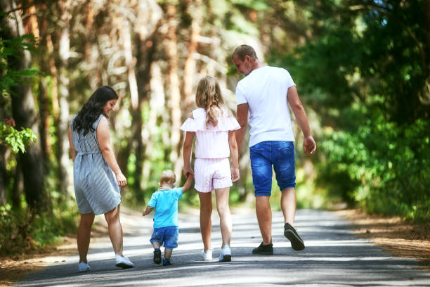 istock Family walking in summer park holding hands 1180019628