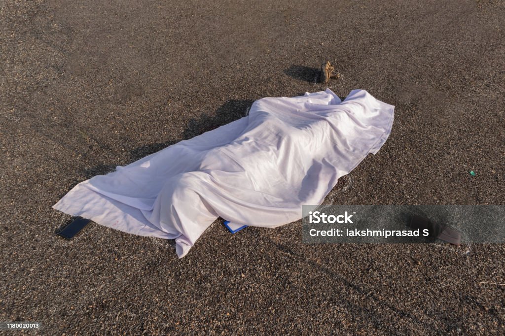 Concept of road accident scene, High angle view of chalk outlined dead body covered under white cloth laying on road. Concept of road accident scene, High angle view of chalk outlined dead body covered under white cloth laying on road Dead Person Stock Photo