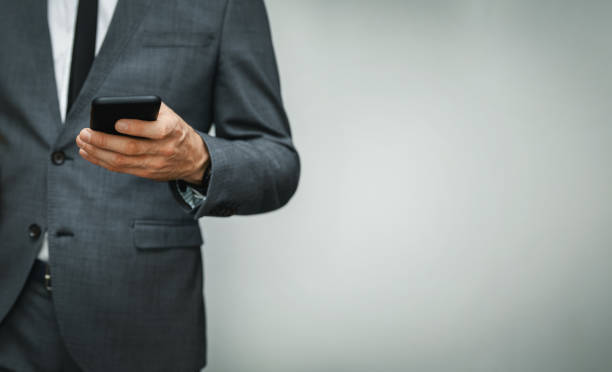 istock businessman wearing suit using phone on gray background. copy space 1180020413