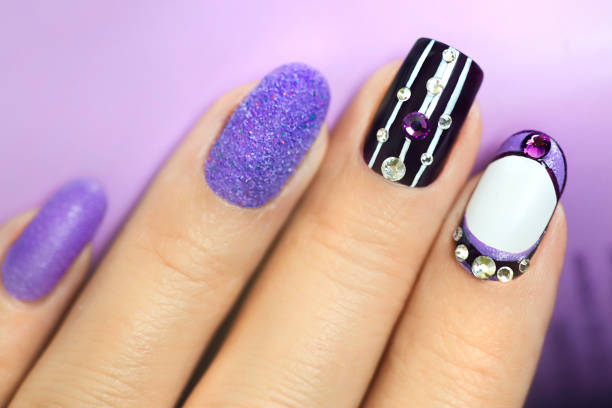 istock Multi-colored manicure with white and lilac varnish on various forms of nails 1180023360