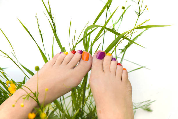 Female legs with a beautiful orange pedicure with a flower on a blue and orange background