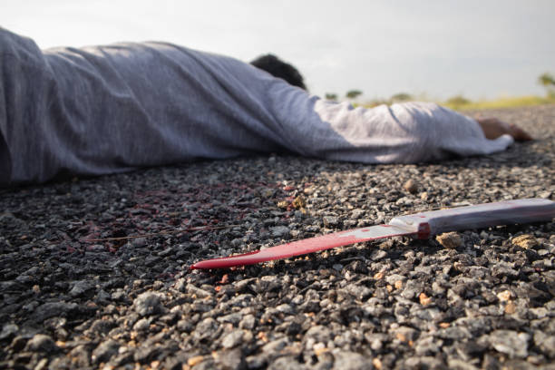 Concept of Crime murder scene, Selective focus of bloody knife on the road with dead body as background lying on Road Concept of Crime murder scene, Selective focus of bloody knife on the road with dead body as background lying on Road. assassination photos stock pictures, royalty-free photos & images