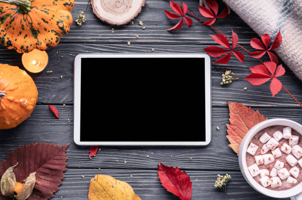 istock Autumn fall holiday background with pumpkin orange leaves cocoa cup tablet computer blank empty screen mock up on brown wooden table, happy halloween thanksgiving shopping sale, above top view 1180031236