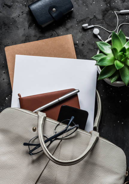 istock Women's bag with office accessories on a dark background, top view 1180031859