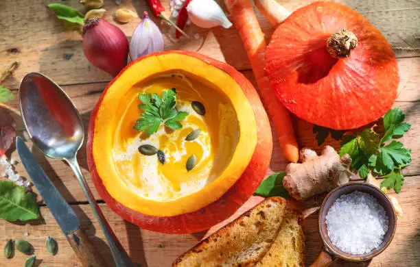 Squash soup served in a pumpkin on rustic wooden table