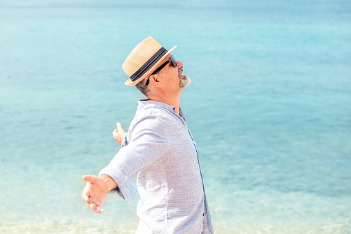 Mature man with outstretched arms enjoying the freedom of the beach.
